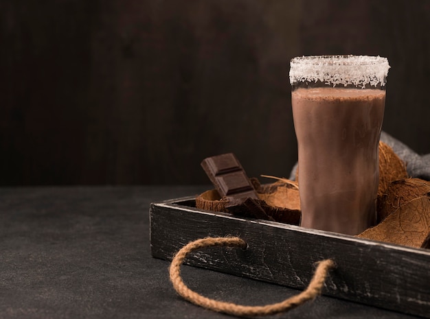 Front view of milkshake glass on tray with chocolate and copy space