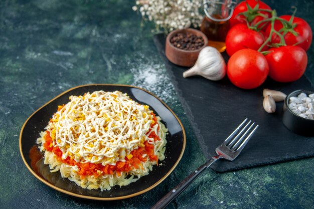 正面図ミモザサラダプレート内プレートに調味料と赤いトマトを紺色の表面にキッチン写真料理誕生日料理休日の食事の色