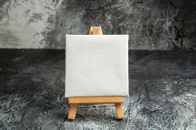 Free photo front view mini white canvas with wooden easel on dark isolated background