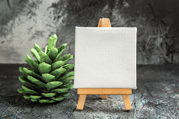 無料写真 ダークに木製イーゼルグリーン松ぼっくりの正面図ミニ白い帆布