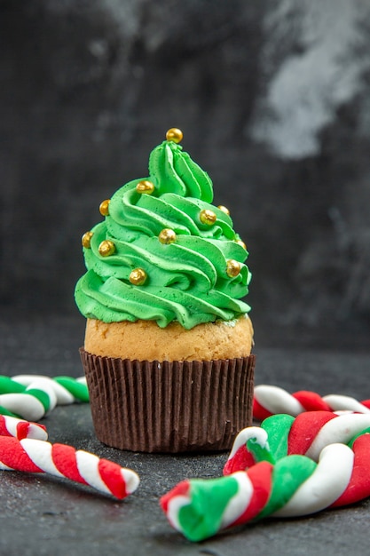 Front view mini xmas tree cupcake and xmas candies on dark background