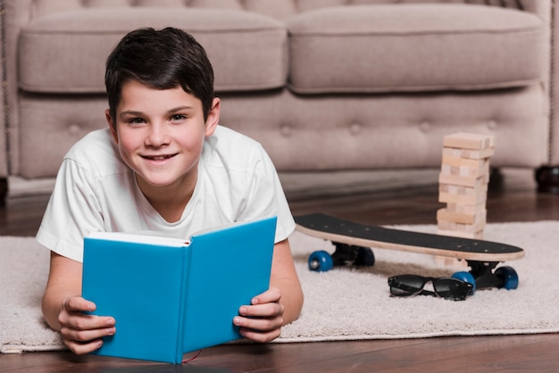 本で床に座っている現代の少年の正面図