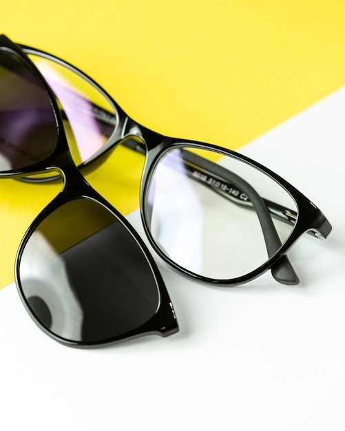 A front view modern dark sunglasses pair on the white-yellow