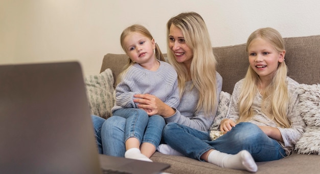 Free photo front view of mom and daughters with technology