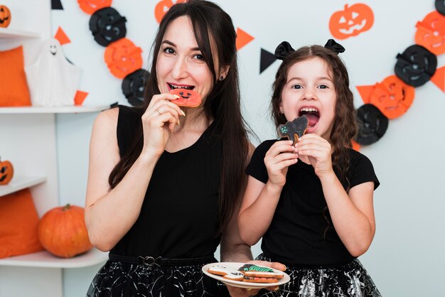 Front view of mother and daughter eating cookies