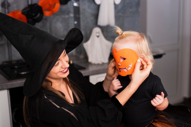 Front view of mother and daughter with pumpkin mask