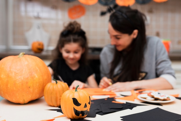 Free photo front view of mother and daughter with pumpkins