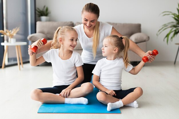 Front view of mother and daughters exercising at home