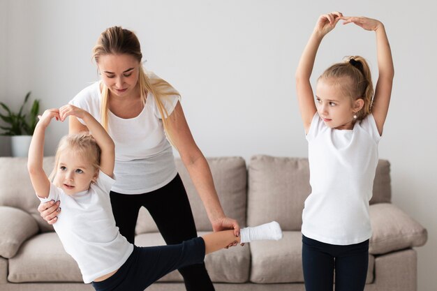 Front view of mother helping daughter practice yoga at home