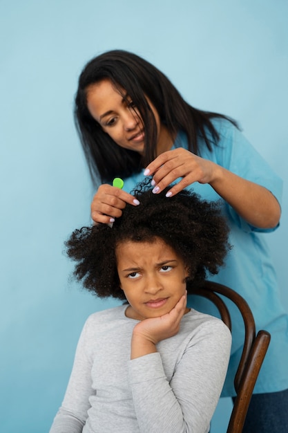 Front view mother helping kid with lice