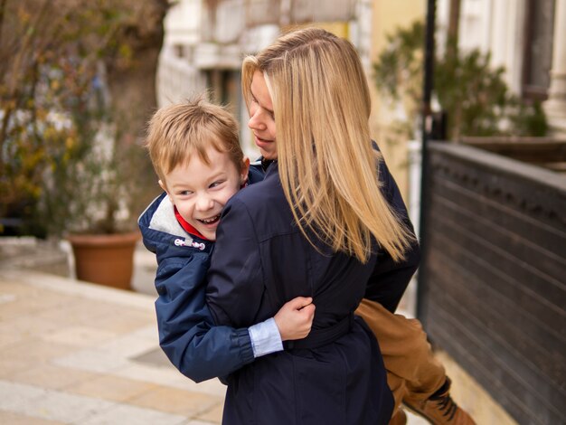 Front view mother holding young boy outdoors