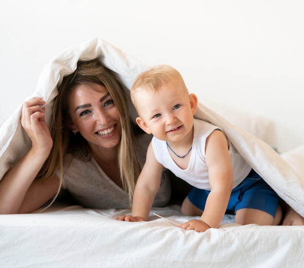 Free photo front view mother and son sitting under blanket