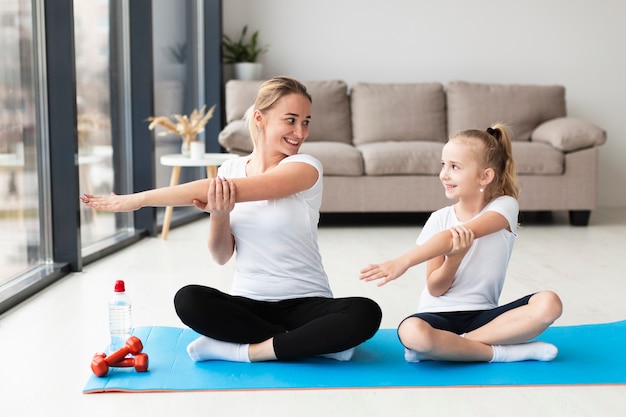 Front view of mother working out at home with daughter