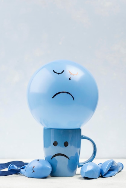 Free photo front view of mug and balloon with frown for blue monday