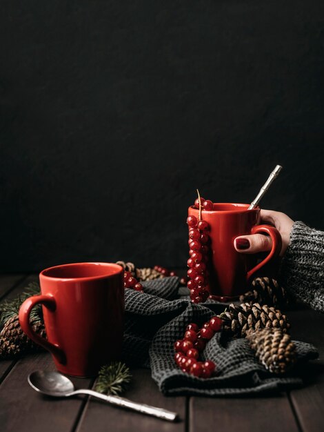 Front view mugs with hot drink and cranberries