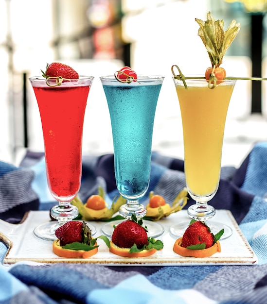 Вид спереди разноцветных коктейлей с фруктовым декором
