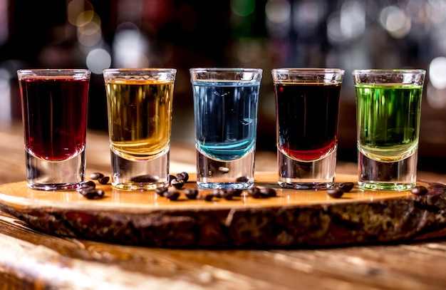 Free photo front view multi-colored shots with coffee beans on a piece of wood