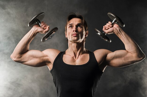 Front view of muscled man lifting weights