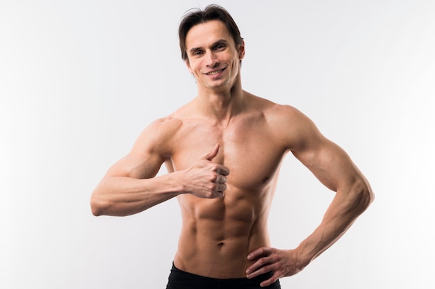 Front view of muscled man posing while giving thumbs up
