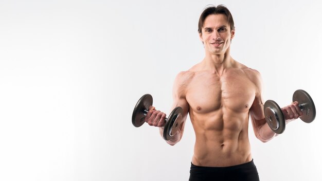 Front view of muscly man holding weights with copy space