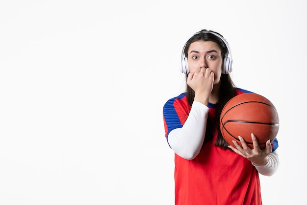 Вид спереди нервная молодая женщина в спортивной одежде с баскетболом