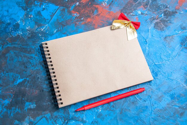 Front view a notebook small bow red pencil on blue background with copy space