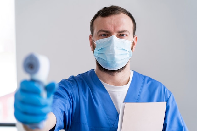 Free photo front view nurse with mask holding device