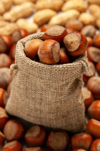 Front view nut composition fresh hazelnuts and peanuts on a white desk nut snack peanut walnut