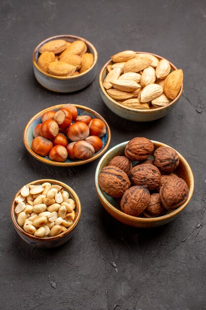 Front view of nut composition fresh nuts inside pots on a dark surface