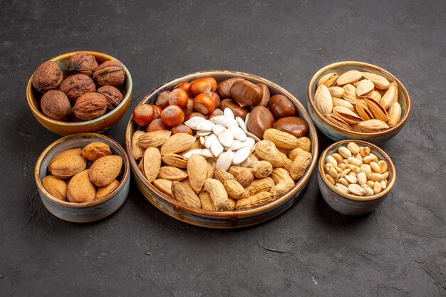 Front view of nut composition peanuts and other nuts on dark-grey surface