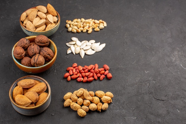 Front view of nut composition with different fresh nuts on dark surface