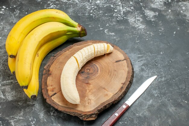 전면 뷰 영양 소스 신선한 바나나 번들 및 회색 배경에 나무 커팅 보드 칼에 다진