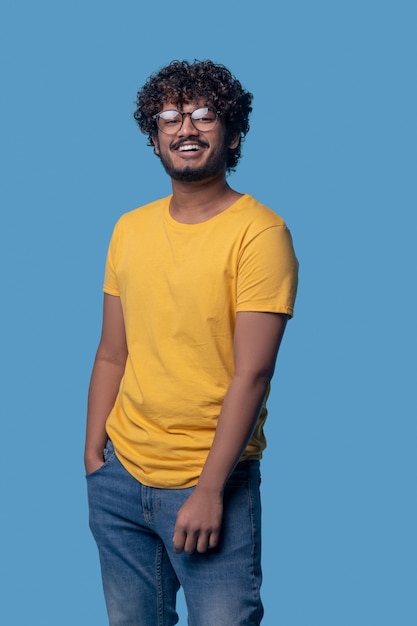 無料写真 カメラに向かって笑っているファッショナブルな眼鏡でうれしそうな若いインド人の正面図