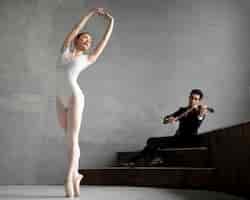 Бесплатное фото Вид спереди балерины, танцующей под музыку скрипача