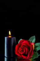 Бесплатное фото Вид спереди темной свечи с красной розой на темной поверхности