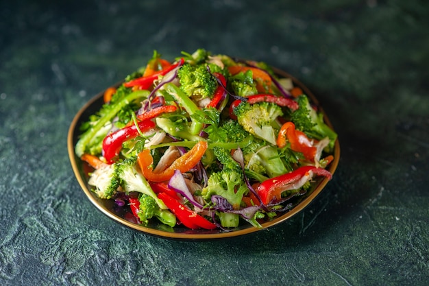 暗い背景にさまざまな食材を使ったおいしい野菜サラダの正面図