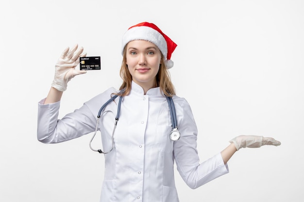 白い壁に銀行カードを保持している女性医師の正面図