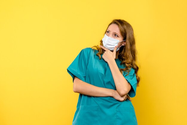 Женщина-врач в маске на желтом полу, вид спереди, пандемический вирус covid- медик
