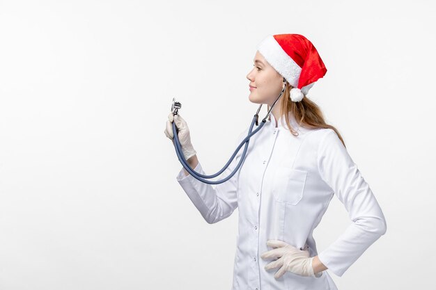 Бесплатное фото Вид спереди женщины-врача с помощью стетоскопа на белой стене