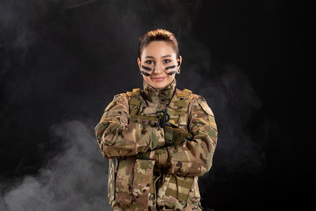Бесплатное фото Женщина-солдат в камуфляже на темной стене, вид спереди