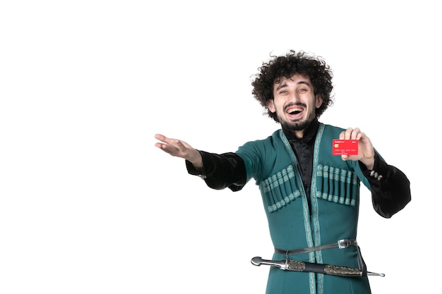 白い背景の上の赤いクレジットカードを保持している伝統的なアゼルバイジャンの衣装で笑っている若い男の正面図春ノウルーズ民族パフォーマーマネーダンサー民族国民