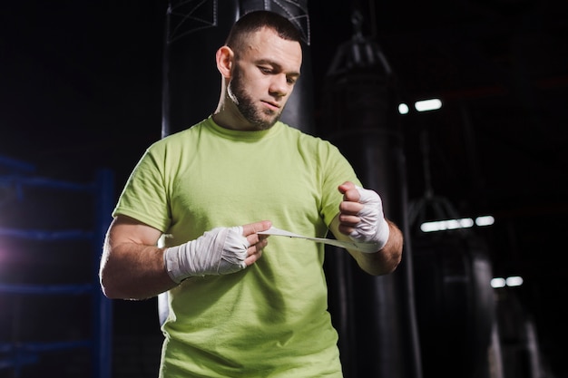 Бесплатное фото Вид спереди боксера мужского пола в футболке надевает защиту для рук
