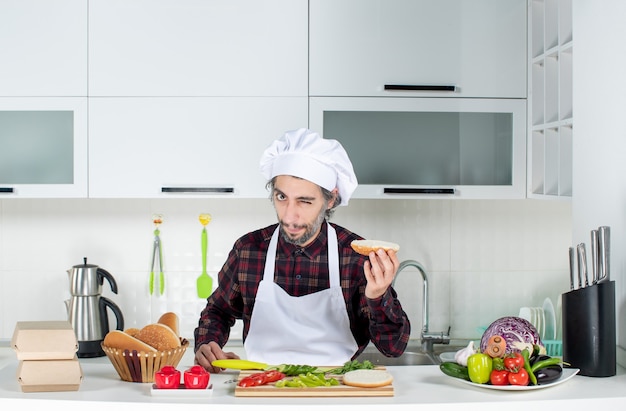 無料写真 キッチンでハンバーガーパンを保持している男性シェフのまばたきの正面図