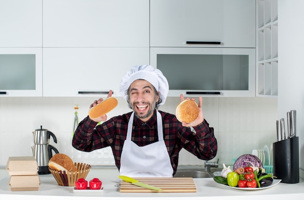 Вид спереди мужского шеф-повара, держащего хлеб обеими руками на кухне