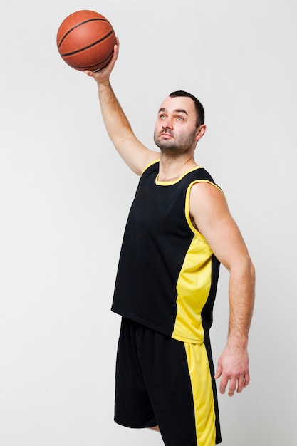 Бесплатное фото Вид спереди игрока мужского пола, подняв баскетбол