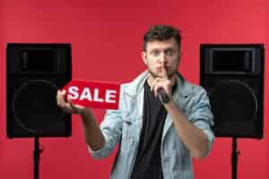 Бесплатное фото Вид спереди певца, выступающего на сцене, держащего распродажу на красной стене