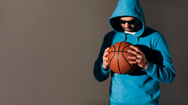 Бесплатное фото Вид спереди человека с капюшоном, холдинг баскетбол с копией пространства