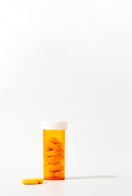 Бесплатное фото Вид спереди пластиковый контейнер с таблетками и копией пространства