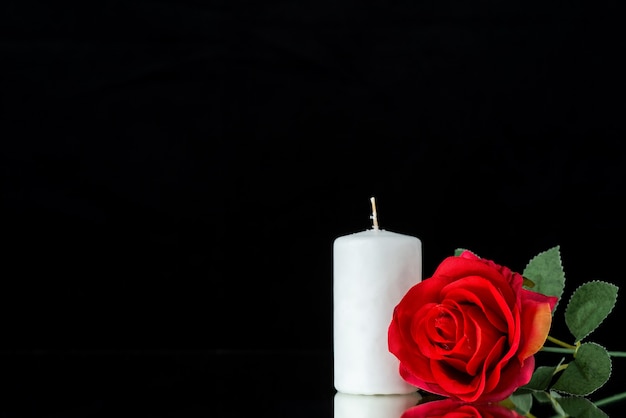 Бесплатное фото Вид спереди белой свечи с красной розой на черном