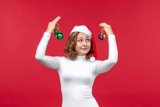 Бесплатное фото Вид спереди молодой женщины, держащей рождественские игрушки на красном